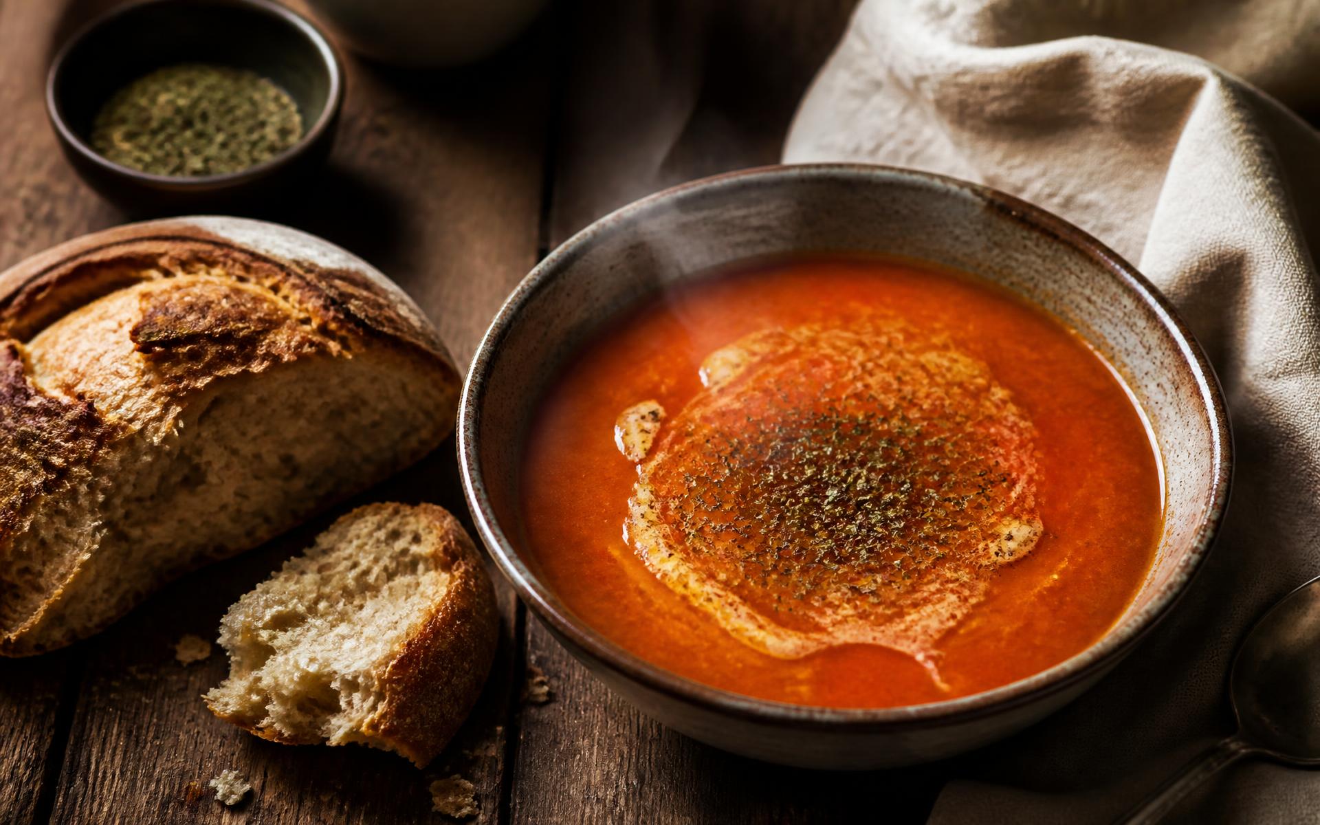 Steaming Turkish tarhana soup in a ceramic bowl beside freshly baked house bread